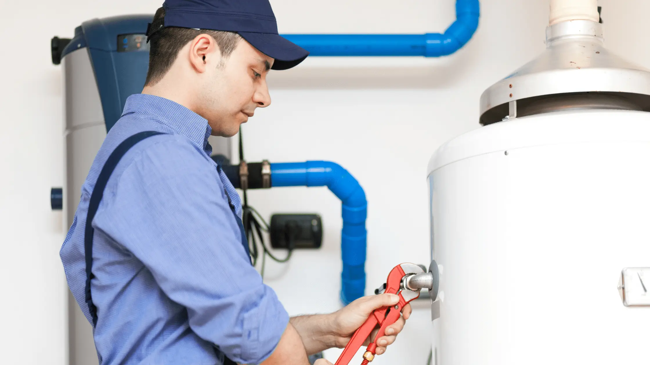 Plumber uses wrench near tank; estimating water heater replacement cost in South Florida.