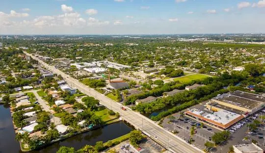 Aerial view of a suburban area with roads, waterways, and commercial buildings, possibly in or near Oakland Park, Florida, where a plumber might operate.